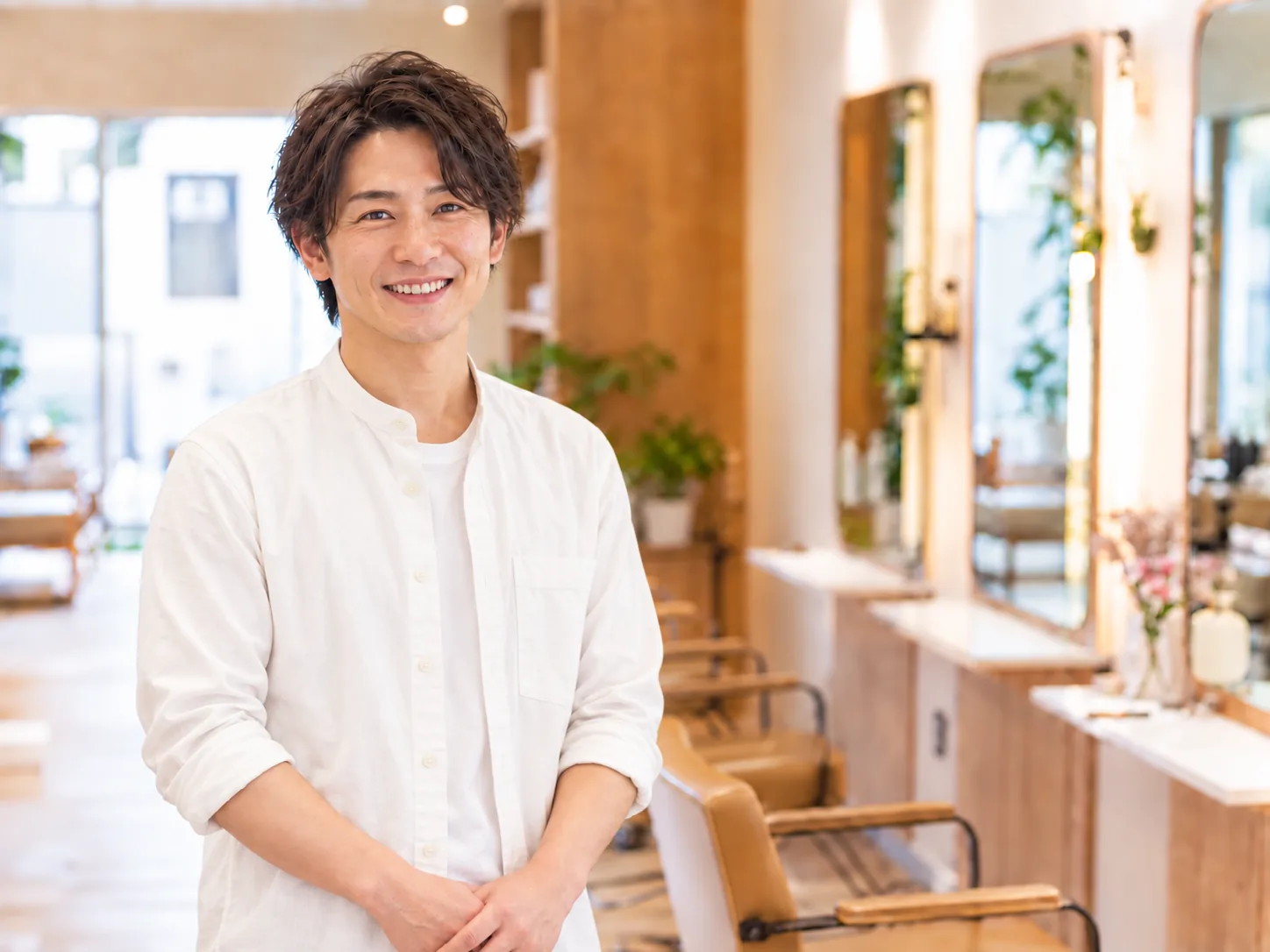 木目調の美容室で微笑む若い男性オーナー